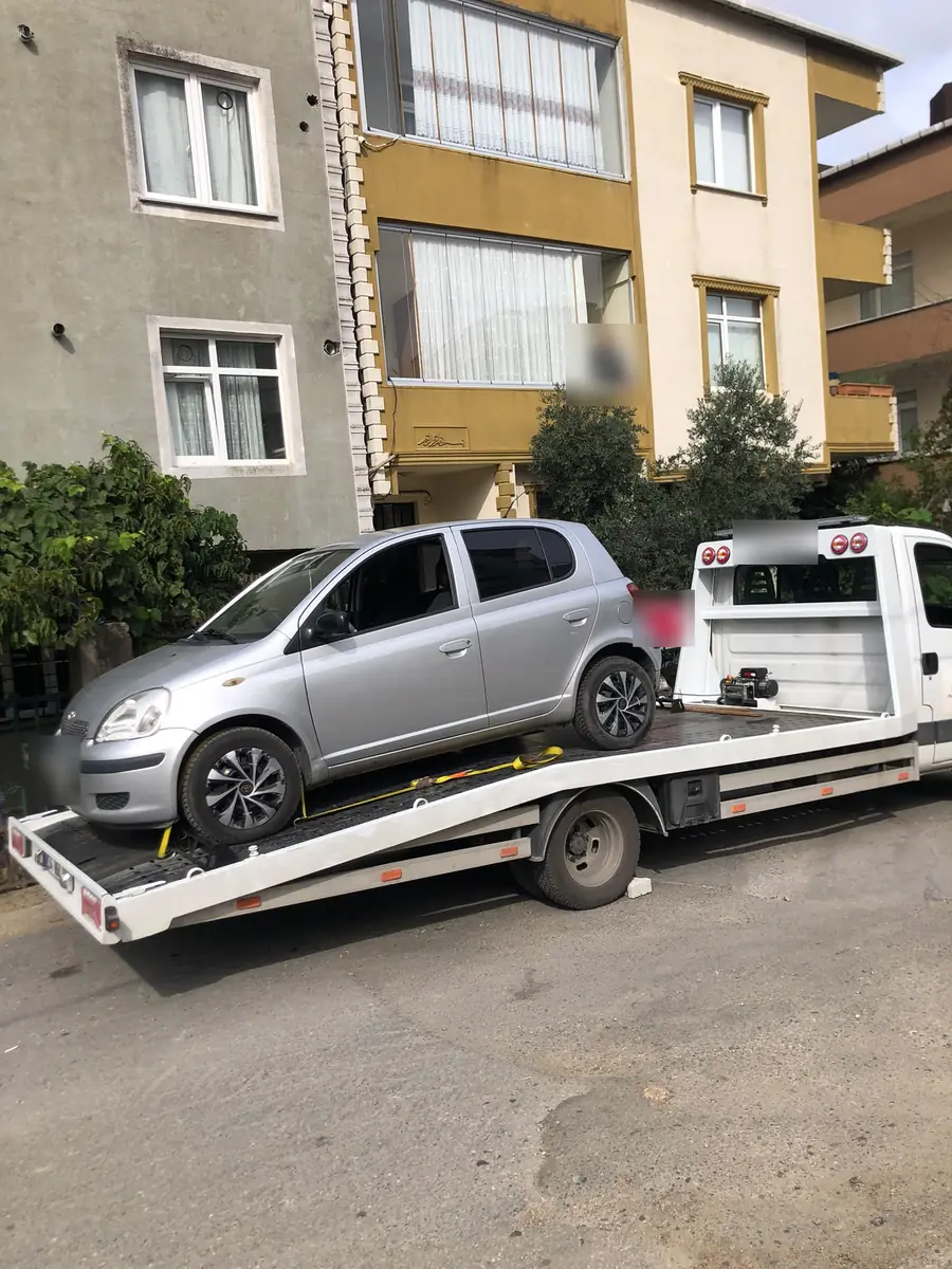 Apartman önünde çekiciye yüklenmiş gri otomobil