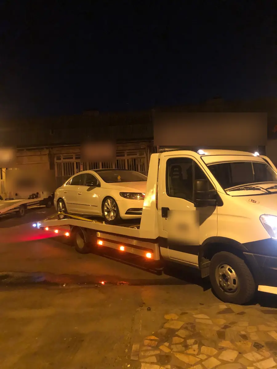 Gece sanayi sitesinde çekici üzerinde beyaz sedan